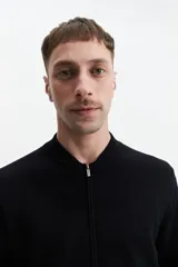 Campera tejida de punto color beige, con cuello rib, puños y bolsillos laterales.