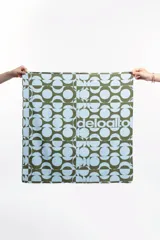 Pañuelo cuadrado de tela con estampado geométrico en tonos verde oliva y celeste.