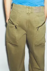Jeans cargo de tiro medio color verde militar, con pernera recta. Presenta bolsillos laterales de plastrón con cierre de cremallera y cierre frontal con cremallera y botón.