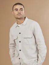 Camisa color verde militar de manga larga con cuello clásico, cierre frontal con botones y dos bolsillos de parche en el pecho.