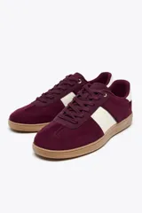 Zapatillas deportivas color borgoña con detalles en blanco y suela color caramelo.