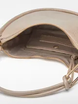 Bolso de hombro tipo media luna color beige, con textura craquelada, cierre de cremallera y asa tubular con pieza metálica.