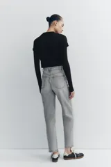 Pantalón de jean gris de tiro alto, corte mom fit, con trabillas y cinco bolsillos. Cierre frontal con cremallera y botón metálico.