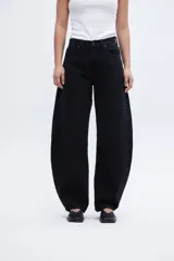 Jean negro de tiro alto, con cintura ajustada y piernas holgadas desde la cadera hasta la rodilla, estrechándose hacia el bajo. Silueta tipo globo, calce balloon.