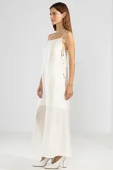 Vestido largo color crema de lyocell, poliamida y lino, con breteles finos, escote recto, lazos en los costados y forro hasta arriba de las rodillas.