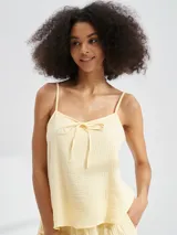 Musculosa color amarillo pálido con tirantes finos y detalle de lazo en el escote.