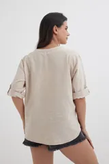 Camisa color crema de algodón con escote en V, mangas 3/4 con trabilla y dos bolsillos con solapa en el pecho.