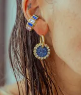 Par de aros colgantes con dije circular de resina con glitter multicolor y borde de strass. El arito es de acero quirúrgico dorado.