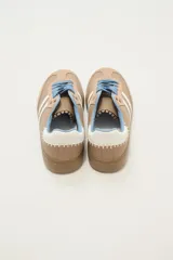 Zapatillas deportivas color rosa con detalles en marrón, cordones marrones y suela color caramelo.