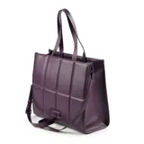 Bolso tipo tote grande color púrpura, con diseño acolchado en símil cuero soft y logo metálico de XL Extra Large al frente. Tiene acceso con cierre, correa regulable y herrajes plateados. El interior está forrado en tela de algodón y poliéster, con un compartimento, un bolsillo con cierre y dos bolsillos abiertos.