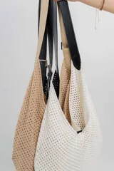 Bolso tejido color crudo con textura calada y correa de eco-cuero negra regulable con hebilla metálica.