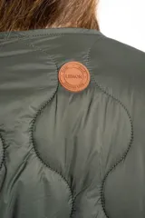 Campera acolchada color verde militar, con cuello redondo y cierre frontal de broches a presión. Presenta un patrón de costuras onduladas.