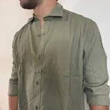 Camisa blanca de lino con corte regular, cuello clásico y mangas largas con puños abotonados.