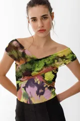 Top con estampado floral en tonos verde, amarillo, rosa y negro. Diseño cruzado con escote off-shoulder y mangas cortas.