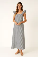 Vestido largo de algodón a rayas verticales azules y blancas, con breteles anchos con volados, escote cuadrado y cierre lateral invisible.