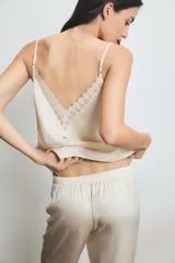 Conjunto de pijama color crema con detalles de encaje en el top. El top es de tirantes finos y el pantalón es largo con volados en el ruedo.