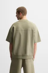 Sudadera negra de corte relaxed fit, confeccionada en tejido interlock de algodón con elasticidad. Tiene cuello redondo, manga corta y bajo acabado en rib.
