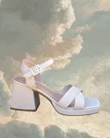 Sandalias de cuero vacuno color blanco hueso, con plataforma y taco cuadrado de 8cm. Presenta tiras cruzadas sobre el empeine y tira con hebilla al tobillo.