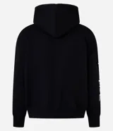 Saco tipo hoodie con cierre frontal de cremallera, color negro, corte boxy y capucha. Presenta estampa de letras en blanco en ambas mangas y un colgante de cruz metálico en el tirador de la cremallera principal.