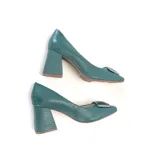 Zapato de cuero color verde azulado, con punta cuadrada, aplique metálico plateado en el empeine y taco ancho con textura geométrica.