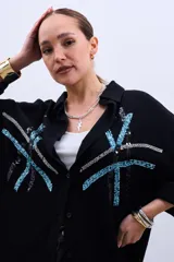 Camisa negra de corte amplio con botones y estampado de líneas con lentejuelas en color celeste y plateado.
