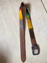 Cinturón de cuero marrón con apliques de tela aguayo con motivos geométricos multicolores.