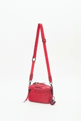 Bandolera negra de nylon matelassé con correa regulable, avíos metálicos, llavero de corazón y dijes desmontables.