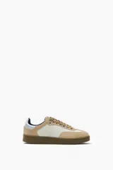 Zapatillas deportivas bajas color beige y blanco, con cordones y suela marrón.