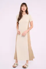Vestido largo de tejido de punto acanalado color beige claro, con paneles laterales lisos en color marrón. Tiene mangas cortas y cuello redondo.