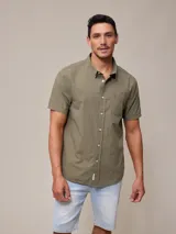 Camisa de manga corta color verde militar, con cuello abotonado y bolsillo en el pecho.