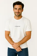 Remera blanca de algodón con estampado de texto negro "it will get better", de corte holgado y cuello redondo.