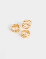 Set de tres anillos dorados de metal con diferentes diseños: uno con tres aros abiertos, otro con tres aros lisos y otro con dos aros lisos.