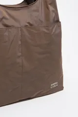 Bolso de mano grande color beige, confeccionado en nylon y con parte inferior de red. Tiene doble asa de mano, asa de tejido regulable, bolsillo interior, cierre de tejido, etiqueta de piel logotipada y acabados metálicos plateados.