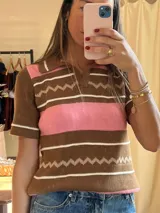 Remera marrón de tejido de punto con rayas horizontales rosas y blancas, cuello polo y mangas cortas.