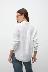 Camisa blanca de lino con cuello clásico, manga larga y bolsillo en el pecho.