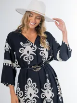 Vestido midi oversized con estampado en fondo negro, cuello tipo camisa, escote en V y tajos laterales.