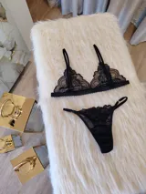 Conjunto de lencería negro de encaje, compuesto por un bralette con breteles regulables y una tanga regulable con corte cola less y entrepierna de algodón.