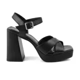 Sandalias de tacón alto color negro, con plataforma y tiras cruzadas sobre el empeine. Cuenta con pulsera al tobillo con hebilla metálica.
