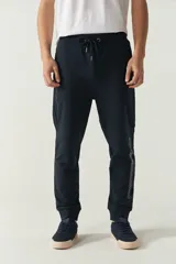 Pantalón de jogging negro de felpa con puños y cintura ajustable con cordón. Presenta logo de goma en la pierna izquierda y bolsillos laterales.