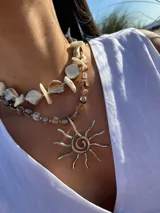 Collar corto con cuentas irregulares de nácar en tonos blanco, beige y marrón claro. Se cierra con cadena de acero quirúrgico y ganchito para regular el largo.