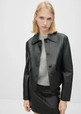 Chaqueta corta de cuero ovino color negro, con cuello camisero, cierre frontal con botones y dos bolsillos de solapa.