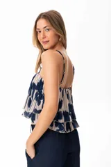 Top de gaza con estampado floral azul sobre fondo crudo, con tirantes finos y volados en el ruedo.