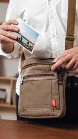 Morral color marrón de tela canvas combinado con detalles en símil cuero. Tiene apertura superior con cierre, dos bolsillos frontales con cierre, bolsillos interiores y un bolsillo trasero con cierre. Incluye correa de galón regulable.