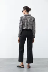 Pantalón negro de tiro alto, corte recto y silueta clásica. Presenta costuras verticales marcadas en la parte delantera de las piernas.