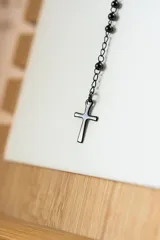 Collar tipo rosario negro con cuentas y cruz colgante en acero quirúrgico.