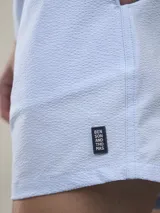 Short de baño verde con estampado de margaritas blancas y cordón ajustable naranja.