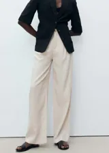 Pantalón de lino color beige, de tiro medio, corte recto y diseño largo.