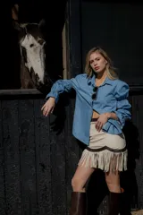 Camisa celeste de jean fino, con cuello clásico, cierre frontal con botones y mangas largas abullonadas con puños elastizados.