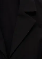 Blusa negra sin mangas con cuello camisero y cierre de lazos en la parte delantera.