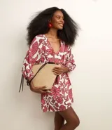 Vestido corto de playa confeccionado en tejido de viscolino estampado con flores. Presenta mangas largas, escote en V cruzado, lazo lateral y elástico en los puños.